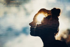 silouette of woman's head against water background