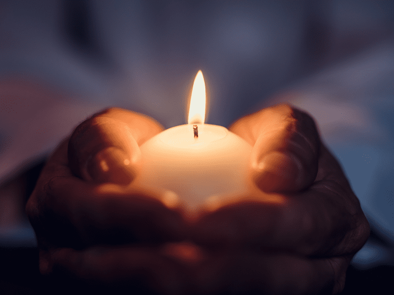 Image of hands holding a lit candle